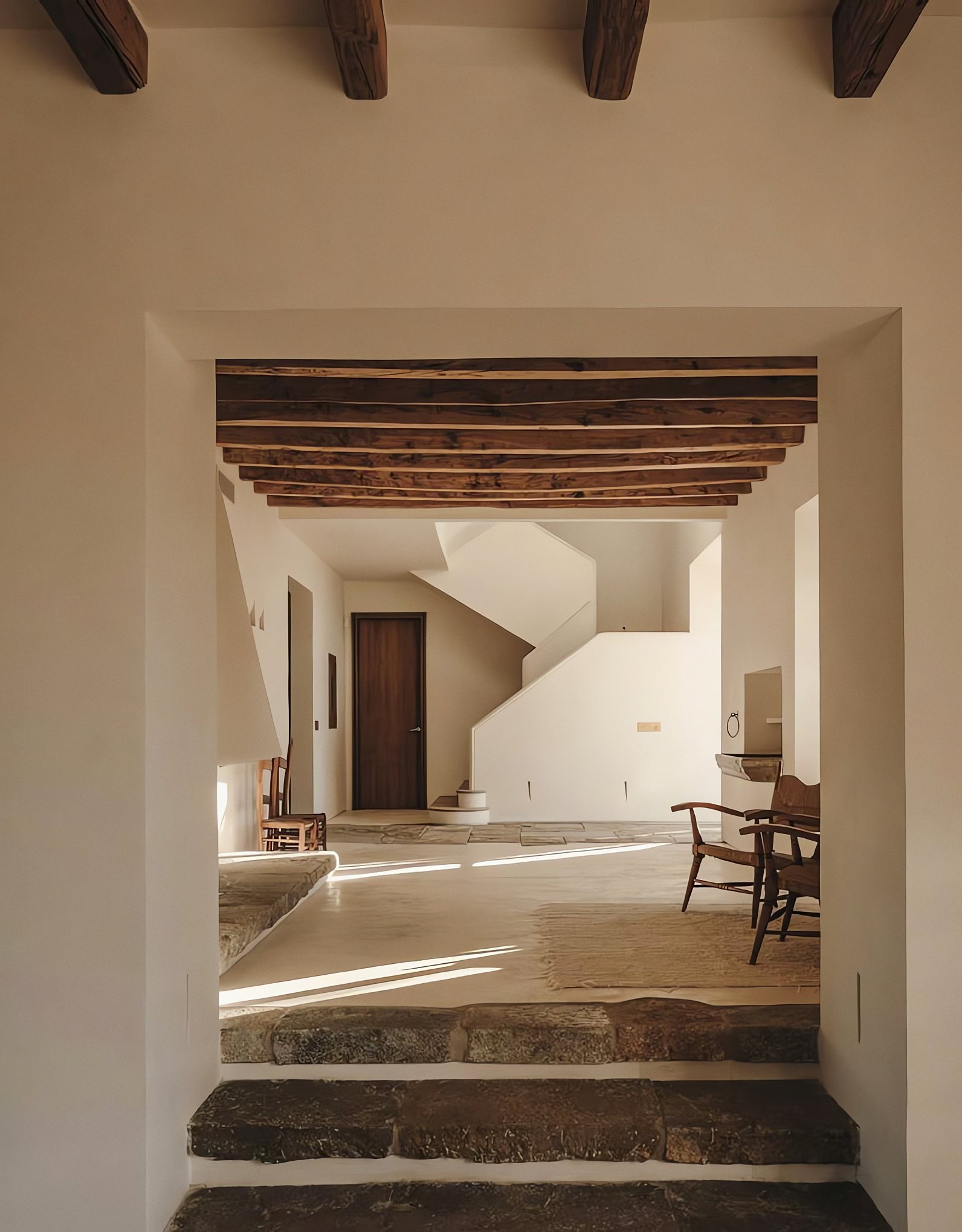 Casa encalada con vigas de madera, escalones de piedra y escalera blanca